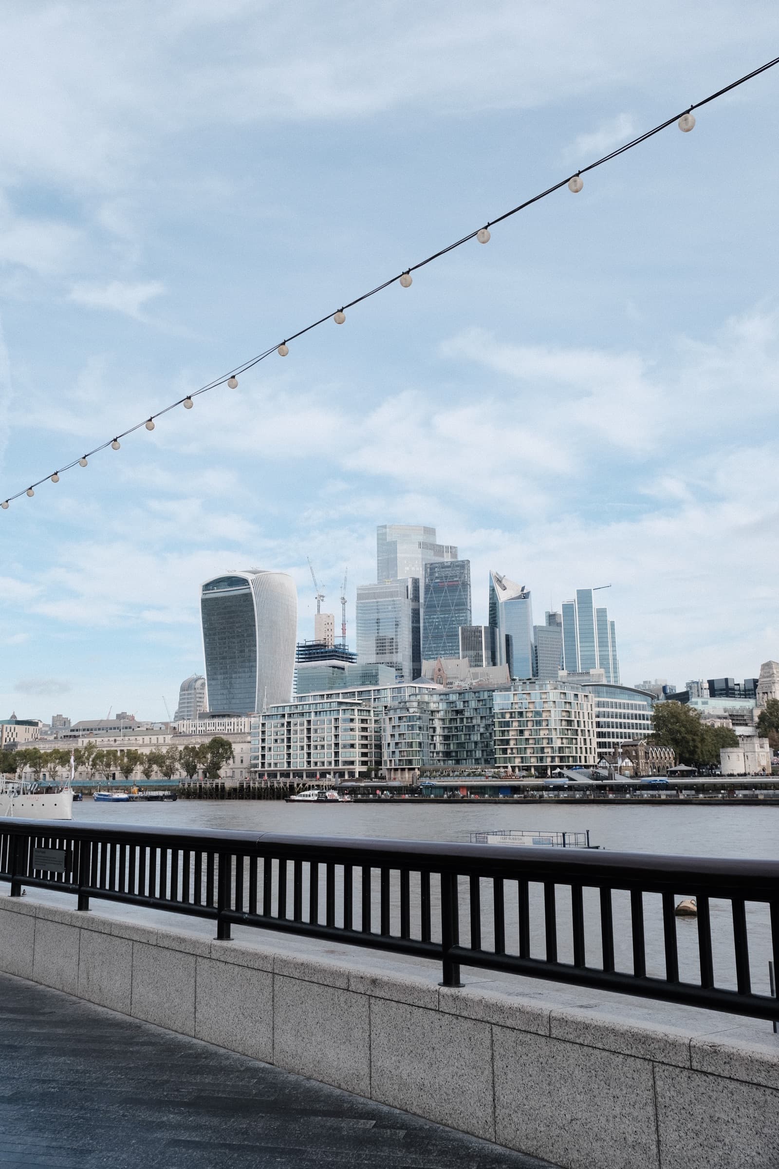 London skyline across the Thames with a line of string lights cutting the frame