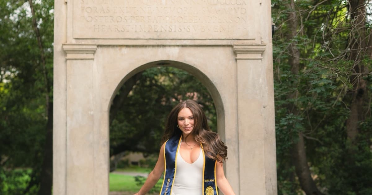 A graduate beneath a stone campus arch, one of the photographs on this site